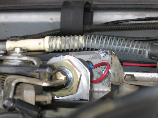 Fabricated engine-bay bracket with coil spring, red wire and throttle linkage