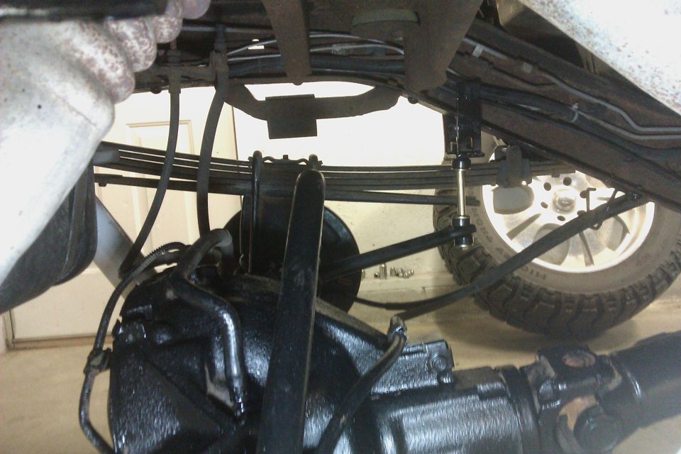 Undercarriage of a vehicle showing suspension components, differential, and tire. The word "SUPERMOTORS" is visible