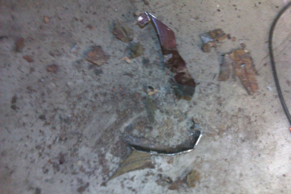 pieces of rusted metal on concrete floor, with a Supermotors.net watermark