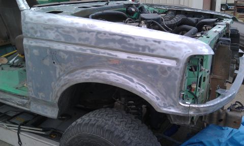 1995 Ford Bronco - The front fender of a Ford Bronco is shown stripped down to primer, revealing the engine bay.