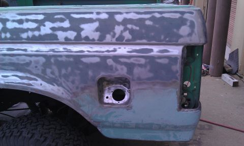 1995 Ford Bronco - This truck's rear quarter panel shows extensive bodywork and primer, with a visible fuel door and an empty taillight housing.