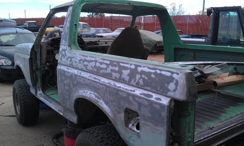 1995 Ford Bronco - This green SUV body is undergoing paint stripping and preparation, revealing primer and sanding marks.