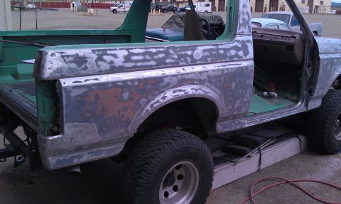 1995 Ford Bronco - The body of a Ford Bronco is shown with primer and body filler, indicating it is undergoing restoration.