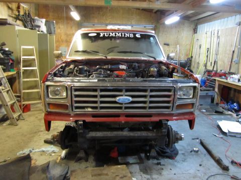 1984 Ford Bronco - Front view of a red Ford Bronco undergoing repairs, with the hood open and engine visible.