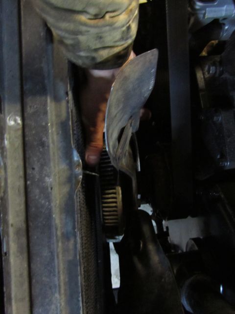 1984 Ford Bronco - Mechanic's hand working on a vehicle's engine belt and pulley system.