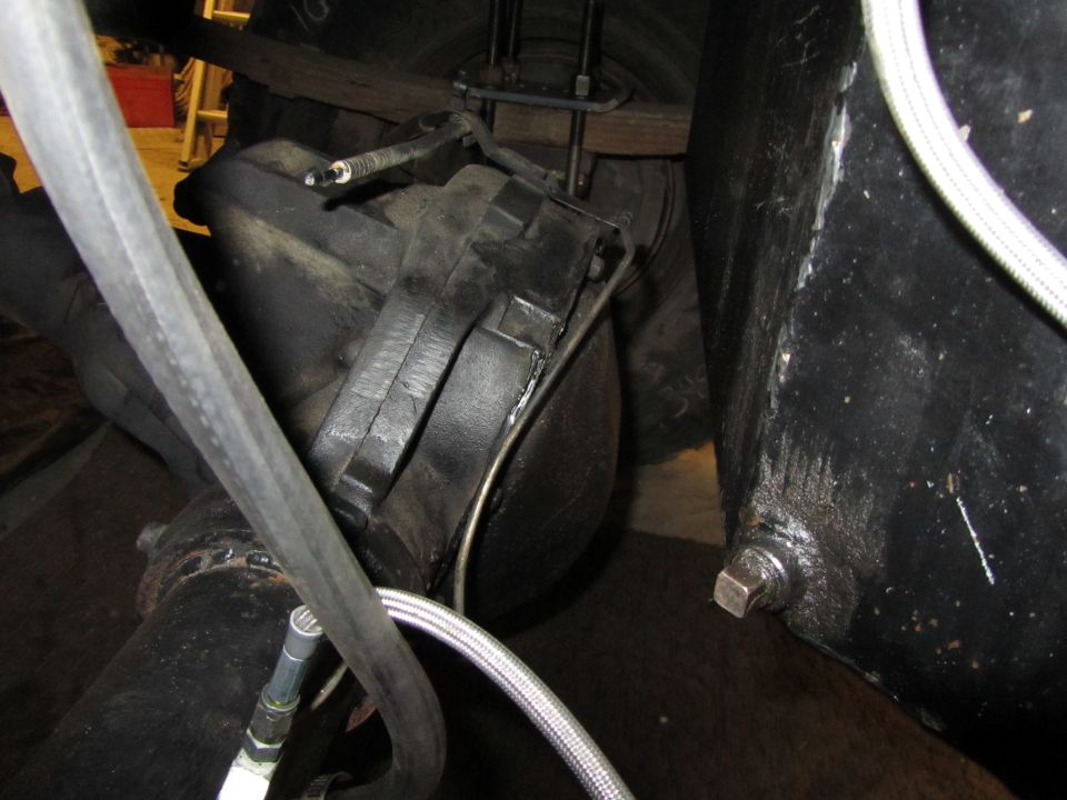 Close-up of a vehicle's rear axle and suspension parts, including brake lines and U-bolts