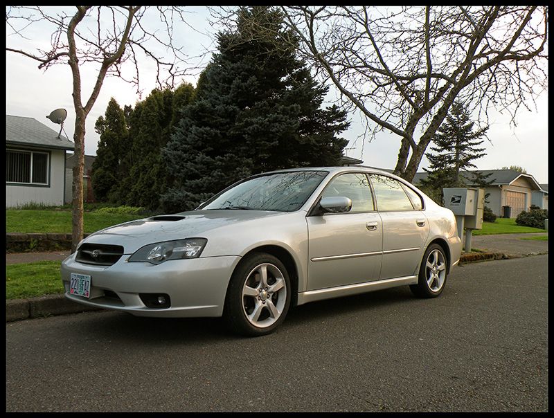 Silver Subaru Legacy GT sedan with hood scoop parked on a residential street, front three-quarter view