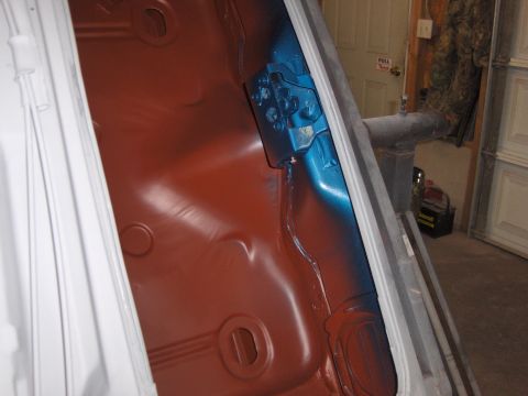 1972 Chevrolet Camaro - The interior of a car trunk shows red primer and blue paint on a metal bracket, with a garage door in the background.