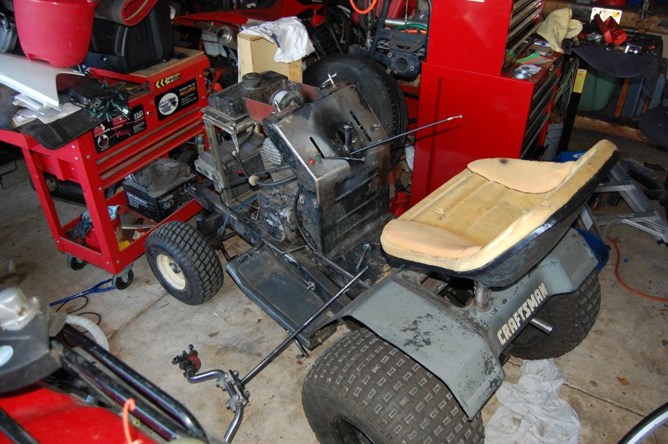 CRAFTSMAN lawn tractor seat and fender, with engine and wheels visible. Red tool cart and another vehicle in background
