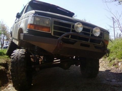 1995 Ford Bronco - This modified Ford Bronco is shown from a low front-left angle, equipped with off-road tires and a custom bumper.