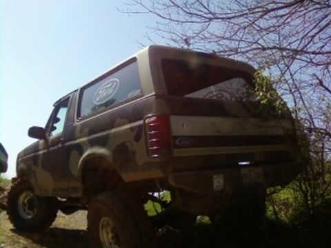 1995 Ford Bronco - This lifted Ford Bronco, painted in camouflage, is viewed from the rear on a dirt path.