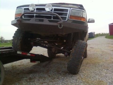 1995 Ford Bronco - This dark-colored SUV, identified as a 1995 Ford Bronco, is shown from a low 3/4 front angle, equipped with an aftermarket bumper and large…