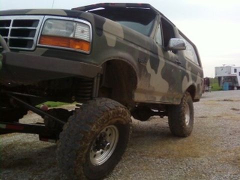 1995 Ford Bronco - Camouflaged 1995 Ford Bronco with lifted suspension and off-road tires parked outdoors.