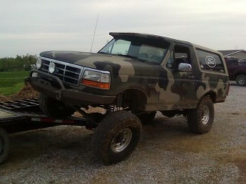 1995 Ford Bronco - A lifted, camouflaged Ford Bronco is being transported on a trailer.