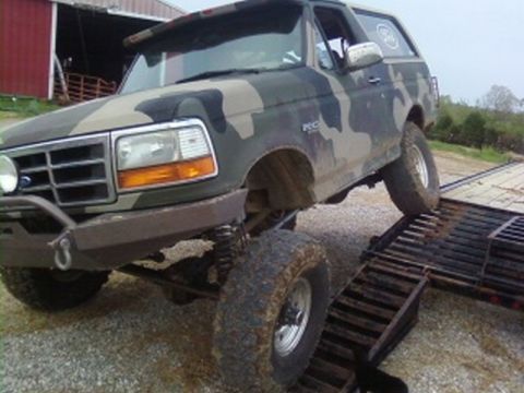 1995 Ford Bronco - This 1995 Ford Bronco, painted in camouflage, is shown driving onto a trailer ramp.