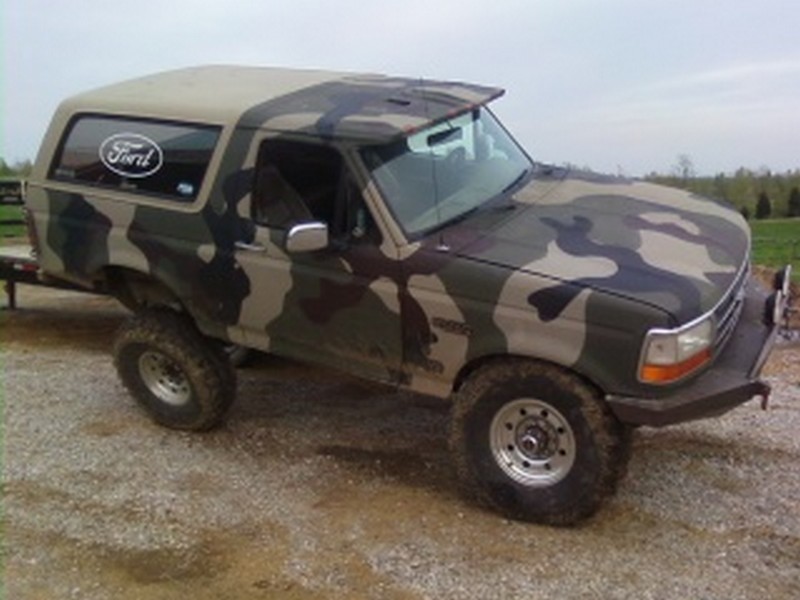 1995 Ford Bronco with camouflage paint, lifted suspension, and aftermarket bumper