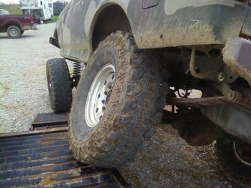Muddy off-road tire on a ramp, another vehicle visible in background