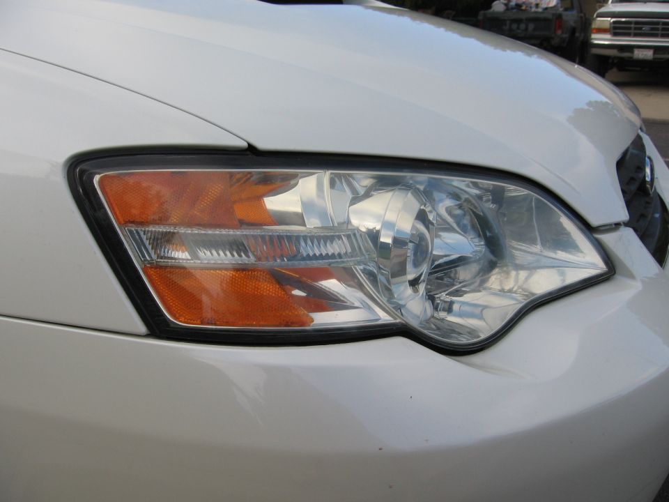 Close-up of a white car's front headlight assembly with orange turn signal
