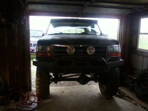 1995 Ford Bronco - A dark 1992 Ford Bronco is viewed from the front, parked inside a garage with another vehicle visible in the background.