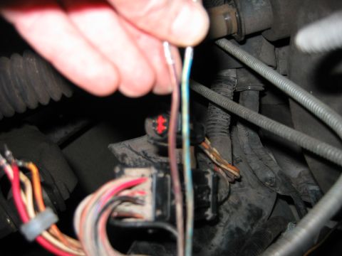 1992 Ford Bronco - A hand manipulates wires connected to a vehicle's electrical system.