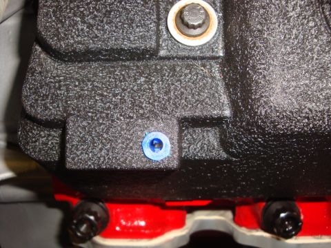 1989 Ford Bronco - A blue plug is inserted into a textured black engine part, with a bolt and washer visible above.