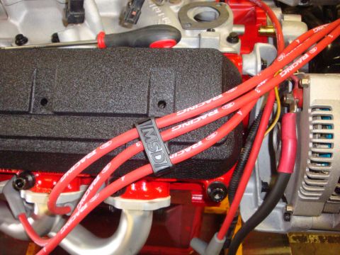 1989 Ford Bronco - Red MSD spark plug wires are routed and secured on a textured black engine component.