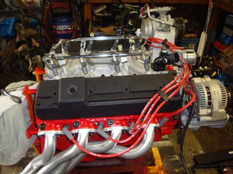 1989 Ford Bronco - A V8 engine assembly sits on a stand, custom headers and a new alternator, ready for installation.
