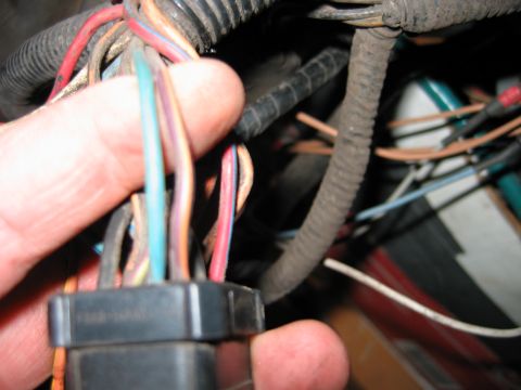 1992 Ford Bronco - Hand holding a wiring harness connector with various colored wires visible.