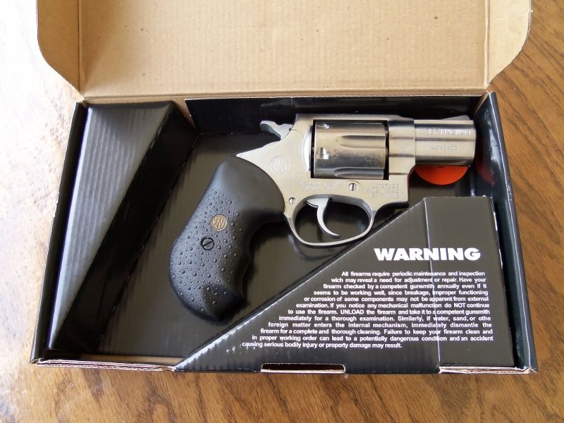 Revolver handgun in its box with a warning label