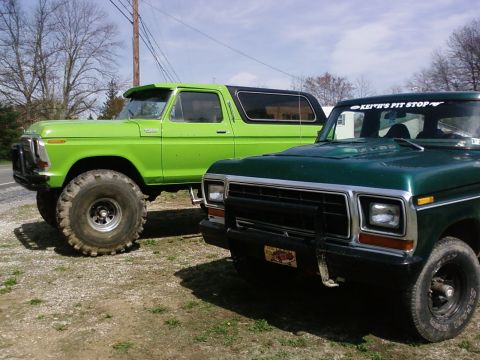 1979 Ford Bronco - Two lifted Ford trucks, a 1979 Bronco and an F-Series, are parked outdoors.