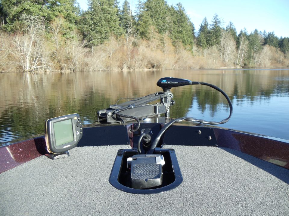 Bow deck of a fishing boat with trolling motor, fish finder and foot pedal on calm water