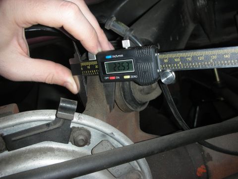 1998 Ford Crown Victoria - A close-up view shows digital calipers measuring a part of a vehicle's rear suspension system.
