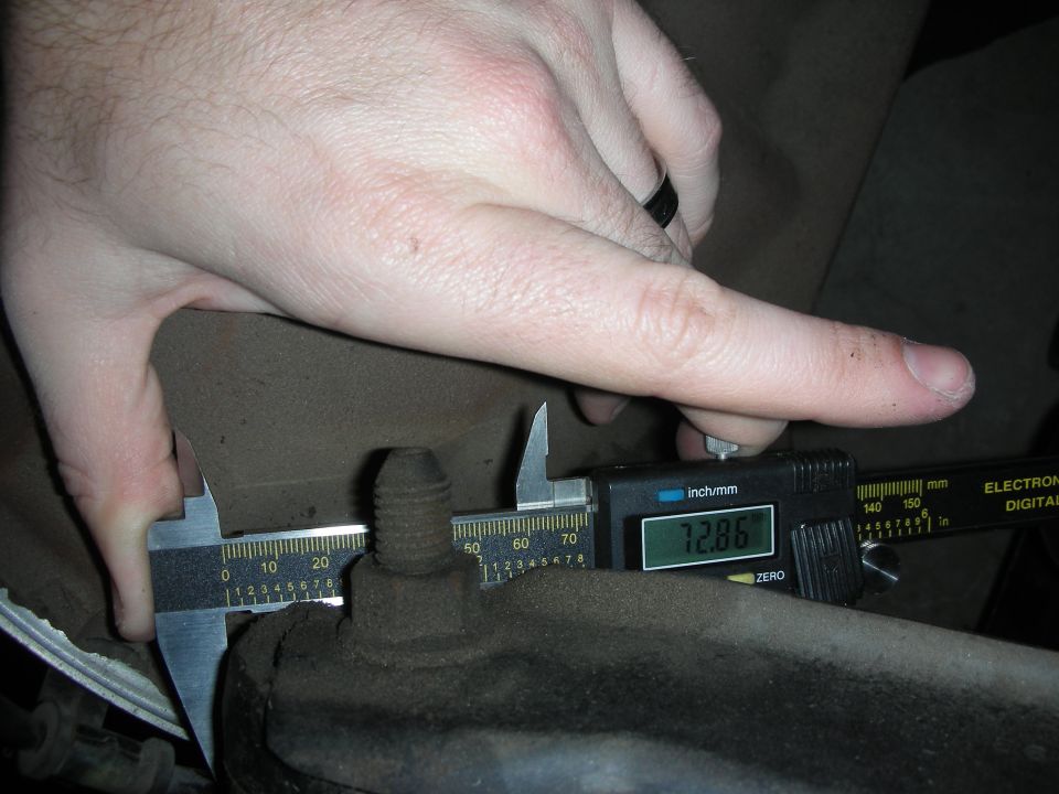 Digital caliper reading 12.86 measuring a threaded suspension stud