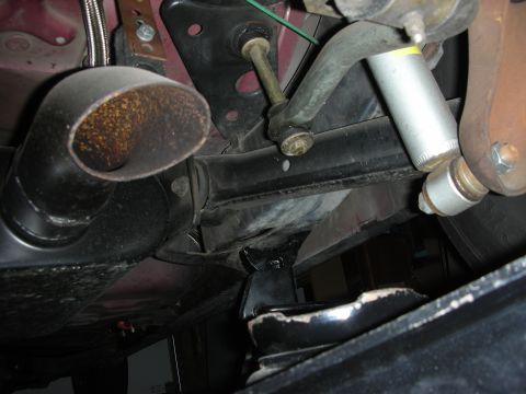 1998 Ford Crown Victoria - Close-up of the undercarriage shows the rear suspension components and exhaust system of a vehicle.