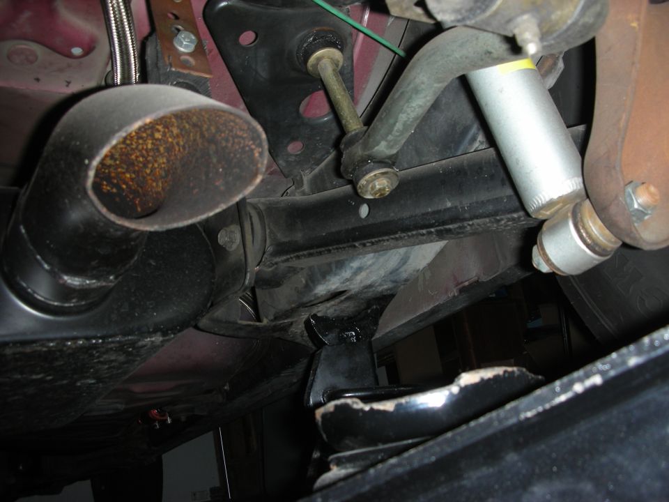Frame crossmember with through-bolt, rusty exhaust pipe and silver shock