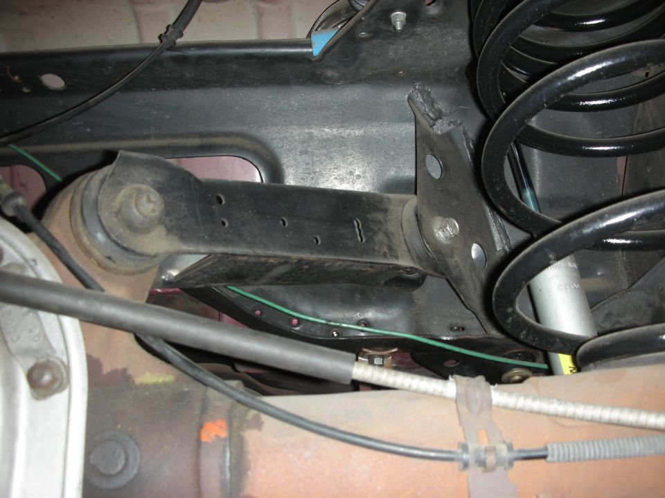 Suspension trailing arm bushing bracket beside coil spring under vehicle