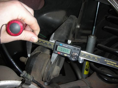 1998 Ford Crown Victoria - Digital calipers are used to measure a rear suspension component, showing a reading of 53.49mm.