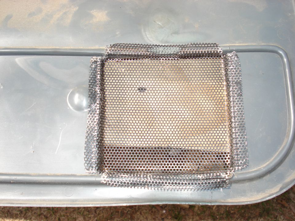 Close-up of a metal mesh patch covering a hole in a gray plastic panel