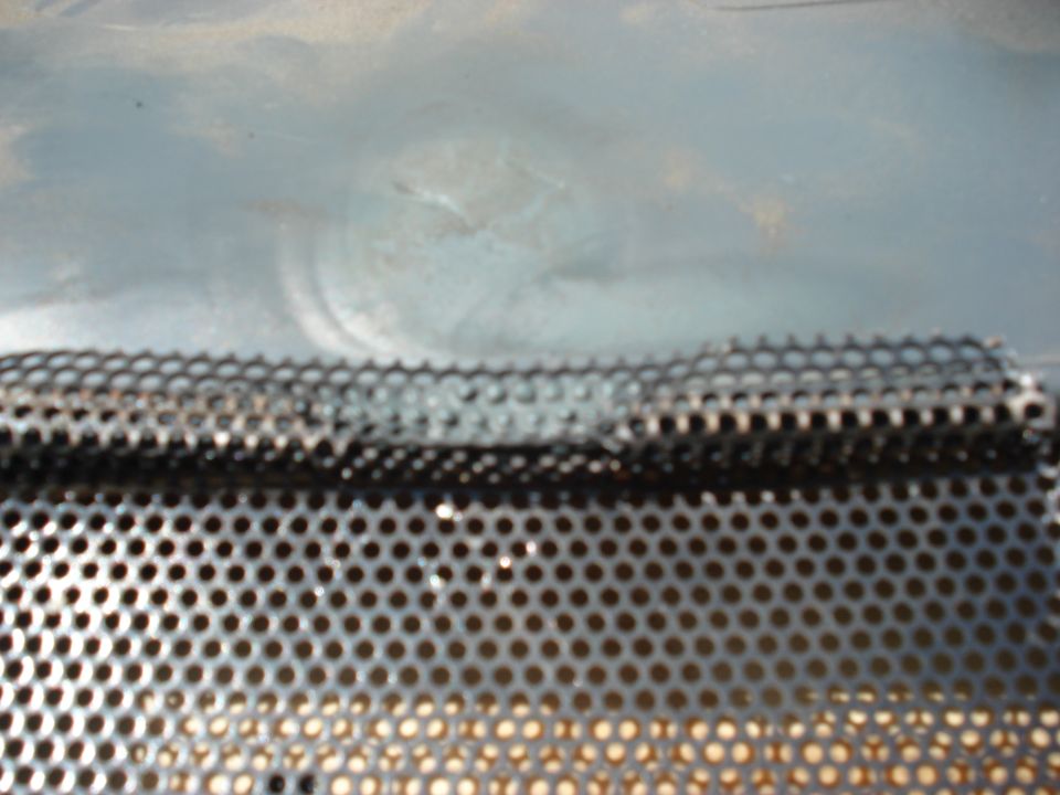 Close-up of a perforated metal panel with a Supermotors logo in the corner
