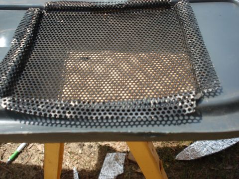 1992 Ford C-350 (Centurion Conversions) - A close-up view of a perforated metal screen, possibly a vent cover, with a textured material visible beneath it.
