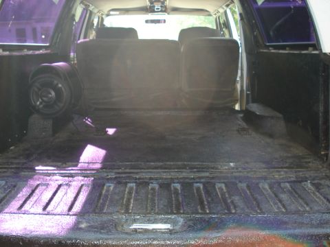 1992 Ford C-350 (Centurion Conversions) - Cargo area of an enclosed truck conversion shot from the open tailgate, with the floor, wheel wells and tailgate all coated in black spray-…