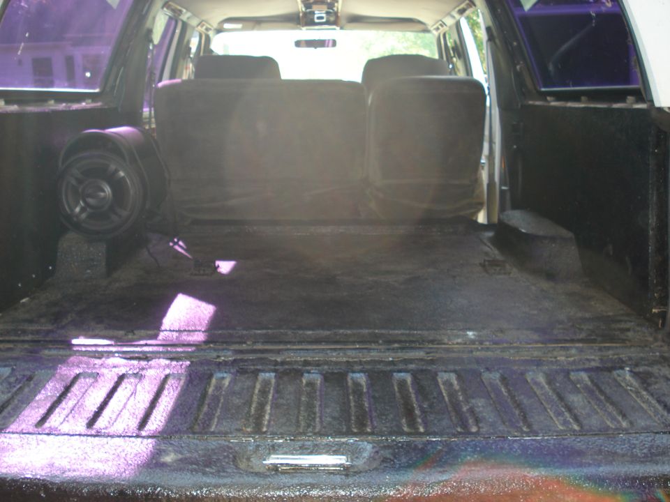Bedliner-coated cargo floor and tailgate with round subwoofer beside rear seat backs