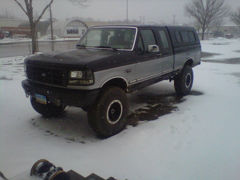1994 Ford F-150 - A lifted Ford F-150 pickup truck with a camper shell sits in a snowy environment.