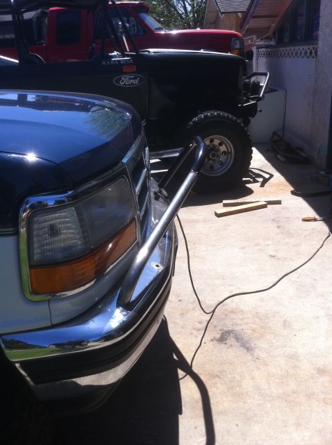 1995 Ford Bronco - The front of a 1995 Ford Bronco is visible, equipped with a chrome bull bar, parked next to another vehicle.