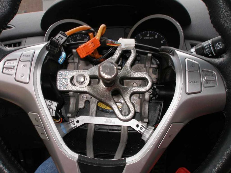 Steering wheel disassembled, showing internal components and wiring. Buttons for cruise control and audio are visible