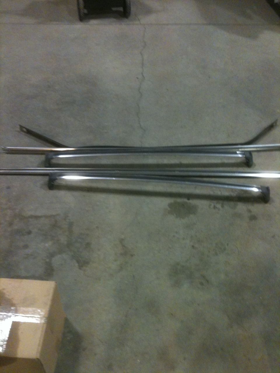 Several chrome trim pieces laid out on a concrete floor