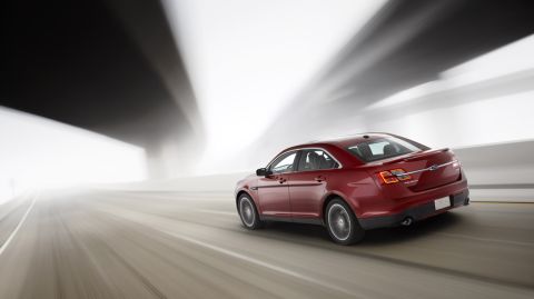 1993 Ford Taurus - A red sedan is captured in motion as it drives through a tunnel with blurred lights.