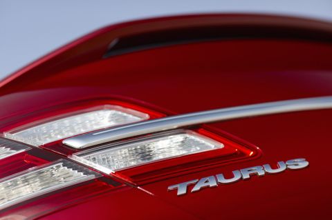 1993 Ford Taurus - Close-up of a red car's rear, showing the 'TAURUS' badging and part of the taillight assembly.