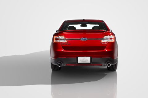 1993 Ford Taurus - Red Ford Taurus sedan, likely a later model, seen from the rear with SHO badging visible.