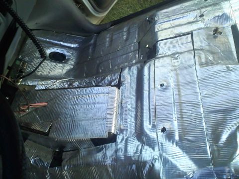 1994 Ford Bronco - The interior floor of a vehicle is covered in soundproofing material, with some wiring exposed.
